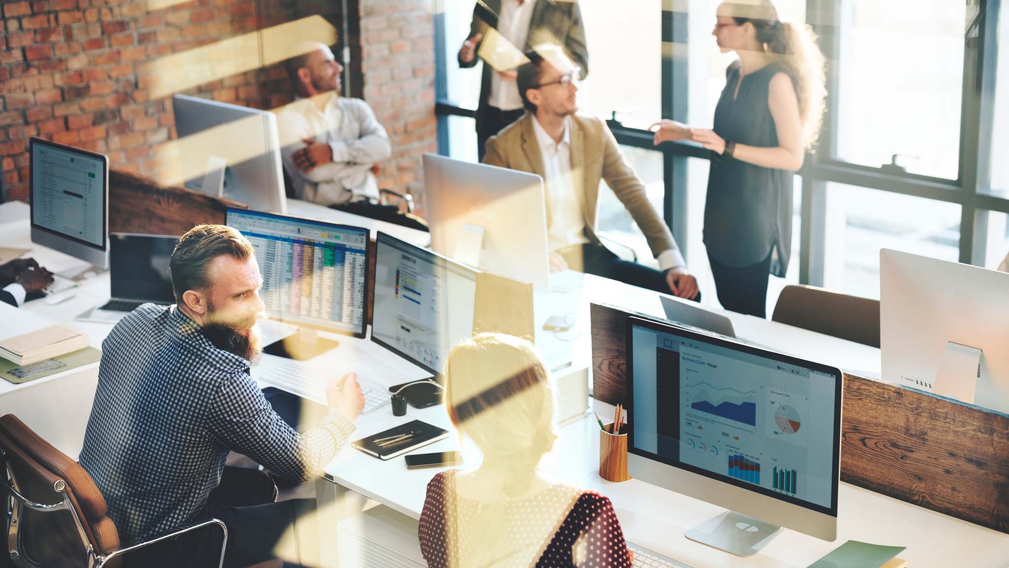 photo of a modern industrial office space with employees conversing and working at computers